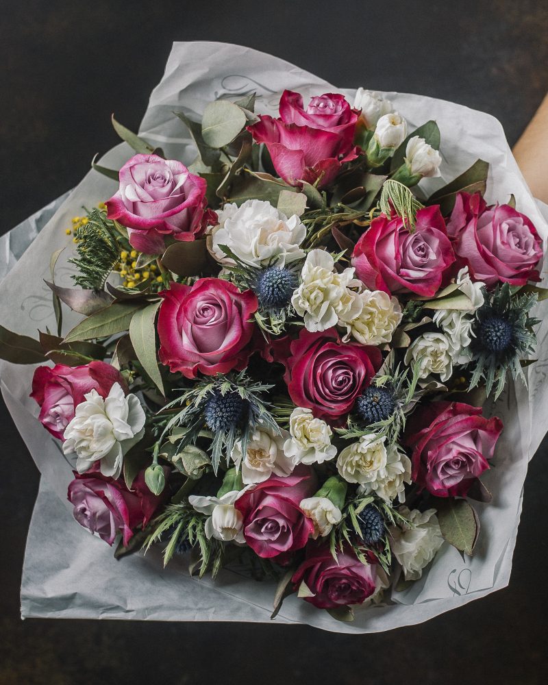 Flower bouquet with pink roses, blue thistle, mimosa and white roses