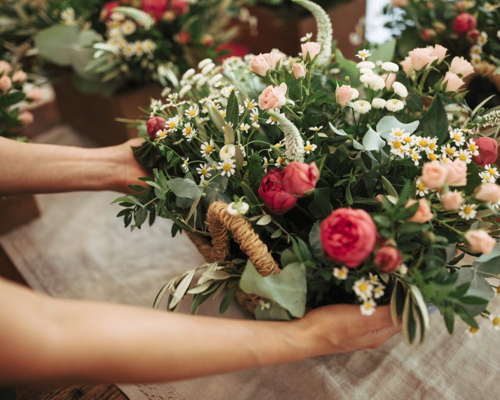 woman-s-hand-holding-basket-pf-fresh-flowers
